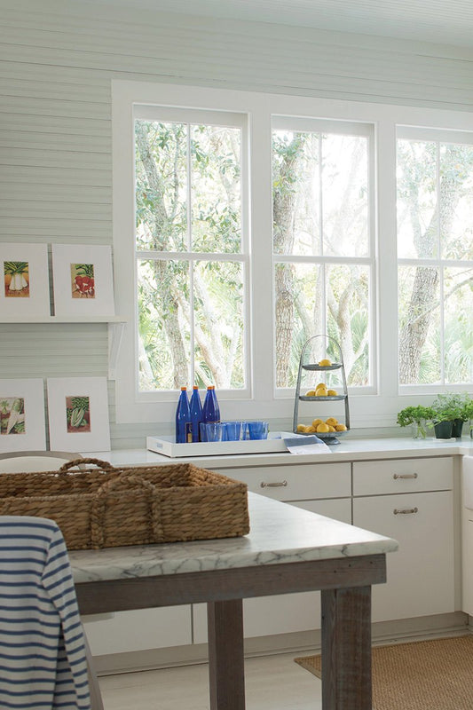 white kitchen with white cupboards, large windows and shiplap panelling 